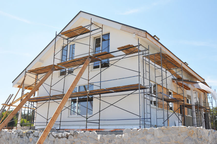 Painting facade house walls after renovation with stucco, plastering, insulation.